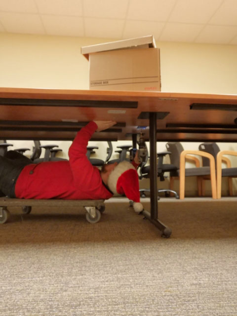 Chris Whitten with santa hat under the table